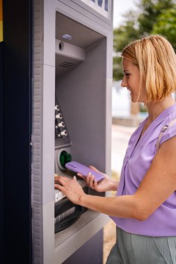 Yunanistan 'da yaz güneşinin tadını çıkaran bir kadın ATM' ye giriyor.
