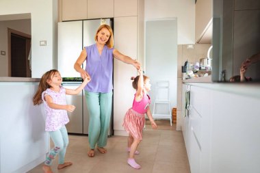 İki neşeli çocuk anneleriyle oynayıp dans ediyor..