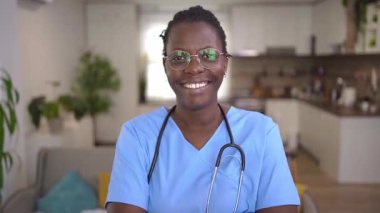 A cheerful medical expert in scrubs engages warmly with a positive demeanor, fostering trust.