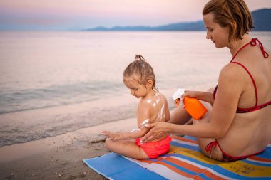 Bir anne yaz güneşinin altında çocuğuyla ilgilenir..
