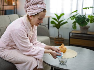 Evde aromaterapi için banyo tuzu döken genç bir kadın.