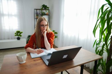 Genç bir kadın dizüstü bilgisayarla çalışırken odaklanmış çalışmaya başlıyor..