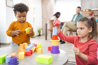 İki çocuk içeride renkli bloklarla yaratıcı bir oyun oynuyorlar..