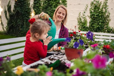 Bir anne ve kız dışarıda çiçek dikmenin keyfini çıkarırlar..