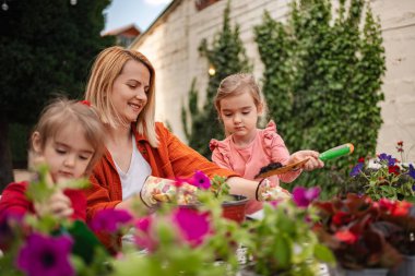 Çocuklar annelerinin renkli çiçekleri dikmesine yardım eder..