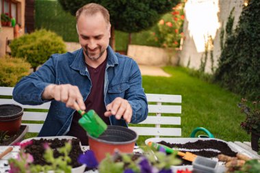Çiçek eken ve dışarıda vakit geçiren bir adam..