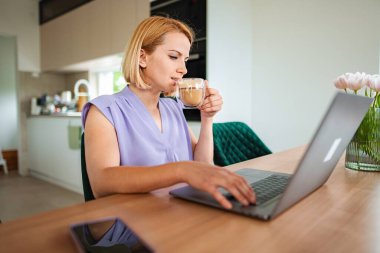 Bir kadın laptopuyla çalışırken kahveden hoşlanır..