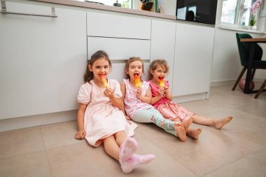 Üç neşeli kız dondurma yerken yerde dinleniyor..