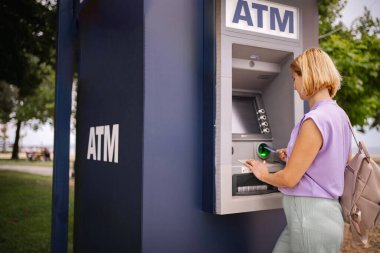 Bir gezgin, sahil kenarındaki güneşli Yunanistan 'da bir ATM ile etkileşime giriyor.