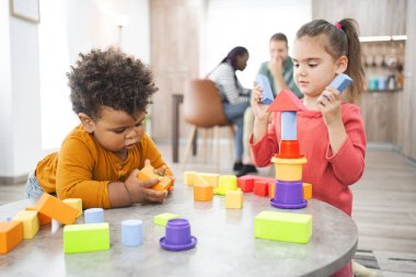 Evlerinde renkli bloklar olan mutlu bir bina inşa eden iki çocuk..
