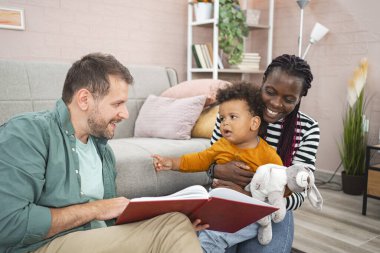 Bir çift, karşılama salonunda çocuklarına kitap okumaktan zevk alır..