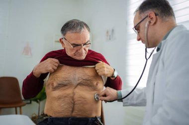 Tıbbi uzman, ziyaret sırasında yaşlı bir adamın sağlığını muayene eder..