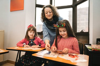 Dil okulunda ilkokul öğrencilerine yardım eden bayan öğretmen.