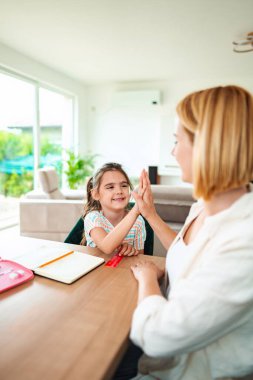 Bir çocuk mutlu bir şekilde evde bir yetişkinle beşlik çakar..