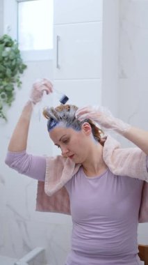 Bir kadın evde rahat bir anın tadını çıkarırken saç boyası sürüyor..