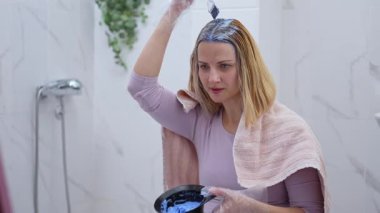 Saçına boya süren bir kadın, neşeyle makyaj anını kucaklıyor..