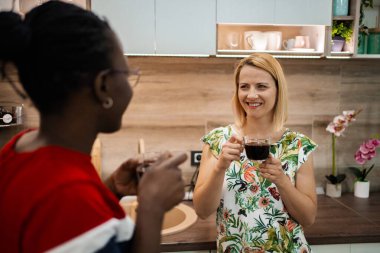 İki arkadaş, güzel tasarlanmış bir mutfakta buharlı kahve fincanlarının keyfini çıkarırken keyifli anları paylaşıyorlar. Biranın kokusu, kahkahalarının ve arkadaşlıklarının sıcaklığını arttırır..