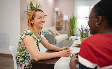 İki arkadaş keyifli bir anın tadını çıkarırlar, şık bir masada karşılıklı gülüşmeler ve hikayeler. Canlı bir dekor onları çevreleyip, bağ ve eğlence için mükemmel sıcak bir atmosfer yaratıyor..