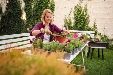 Kadın neşe içinde bahçedeki canlı çiçekleri besliyor..
