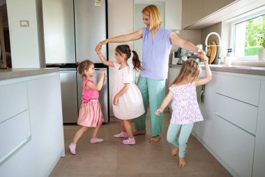 Bir anne içeride neşeli kızlarıyla dans etmekten hoşlanır..