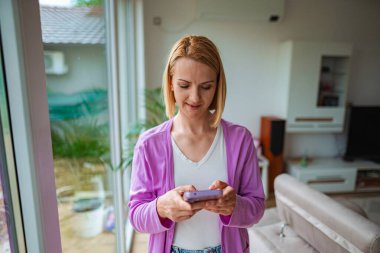 Modern bir ortamda akıllı telefonuna dalmış bir kadın.