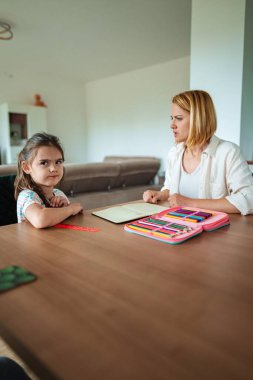 Bir çocuk ve yetişkin masada düşünceli bir anı paylaşır..
