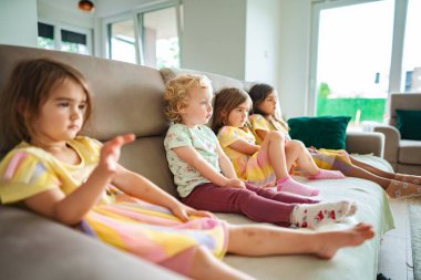 Dört genç kız kanepede rahatlar, neşeli anlar paylaşırlar..