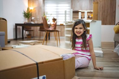 Genç bir kız karton kutuların arasında mutlu mesut otururken, ikinci bir çocuk sıcak ve davetkar bir evde mobilya montajında çalışıyor. Atmosfer heyecanla dolu..