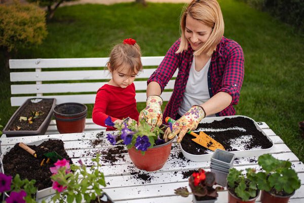 Mother and daughter enjoy planting flowers together outdoors.