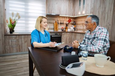 Bir doktor evde yaşlı bir adamla sağlığı tartışır..