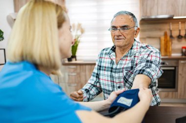 Bakıcı hemşire mutfakta kan basıncını ölçer.