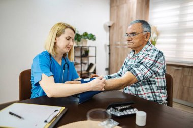 Hemşire klinikte yaşlı erkeklerin kan basıncını ölçüyor.