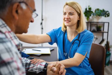 Hemşire klinikteki yaşlı adama bakım ve destek sağlıyor.