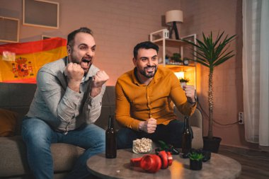 İki arkadaş heyecanlı bir spor karşılaşmasında favori takımlarına tezahürat yaparken heyecana kapılırlar. Sıcak oturma odaları, aperatifler ve içeceklerle dolu, atmosferi geliştirir..