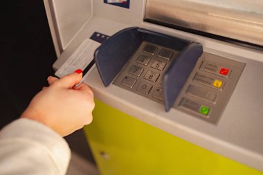 Bir el ATM klavyesine yakın bir banka kartı tutuyor, bir işleme hazırlanıyor..