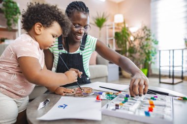 Neşeli bir anne ve çocuk evde renkli sanatlar yaratıyor..