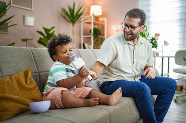Mutlu bir çocuk kanepede mikrofona şarkı söylüyor..