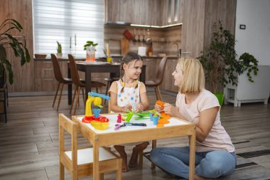 Bir anne ve kızı bir masada eğlenceli bir zanaat seansı düzenler, plastiklerle renkli sanatlar yaratır ve birlikte kaliteli zaman geçirmekten zevk alırlar..