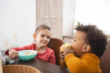 Kardeşler yemek masasında keyifli bir kahvaltı anı paylaşırlar..