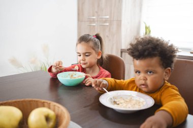 Mutfak masasında iki çocuk kahvaltı yapıyor..