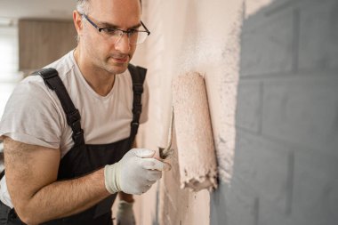 Bu sahnede bir adam boya silindiriyle duvar boyarken görülüyor. Yüzeyi sistemli bir şekilde kaplayarak, pürüzsüz ve eşit bir şekilde yeni bir kat boya uyguluyor. Duvar, silindirin her vuruşuyla yeni bir renge dönüşüyor..