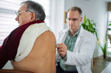 Bir sağlık uzmanı, yaşlı bir adamın rutin kontrollerini yapar..