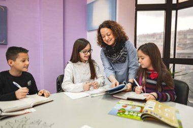 Dil okulunda ilkokul öğrencilerine yardım eden bayan öğretmen.