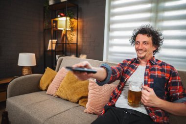 Rahatlamış adam evde boş zamanlarının tadını çıkarıyor, televizyon izliyor ve bira içiyor.