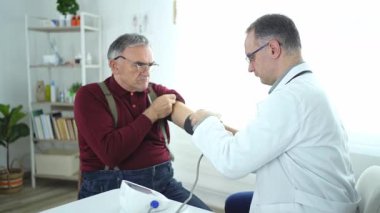 Yaşlı bir beyefendi sakince otururken sağlık kontrolünden geçiyor..