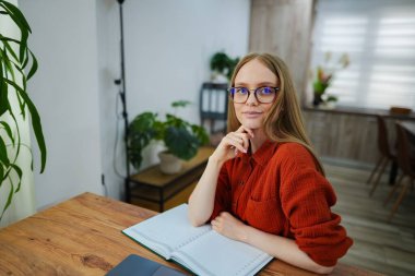 Gözlüklü genç bir kadın masasında sonraki adımlarını düşünüyor..