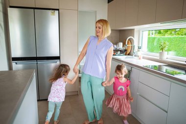 Neşeli bir anne, mutfakta kızlarıyla etkileşime girer..