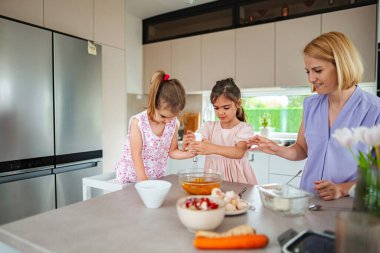 İki çocuk ve anneleri evde birlikte yemek yapmaktan hoşlanırlar..