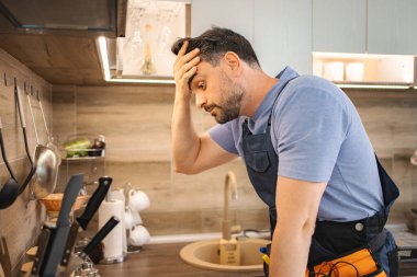 Tesisatçı işte kötü bir gün geçiriyor. Hayal kırıklığı içinde başını tutuyor.