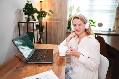 Bir kadın masasında sıcak bir anın tadını çıkarır, çalışırken sıcak bir içki yudumlar..